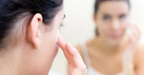 Person applying cream to their face while looking in a mirror