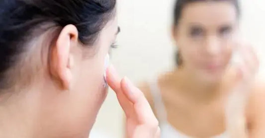 Person applying cream to their face while looking in a mirror