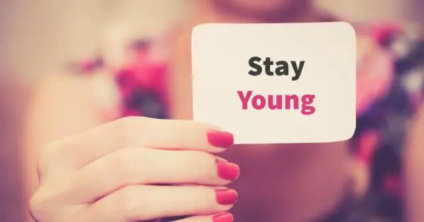 A hand holding a card that says 'Stay Young' with colorful background
