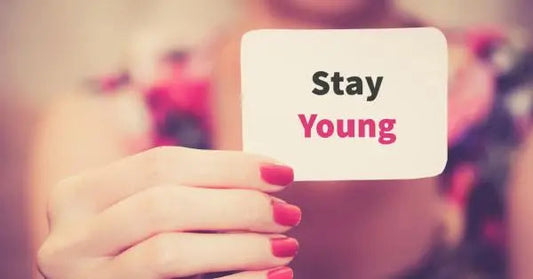 A hand holding a card that says 'Stay Young' with colorful background