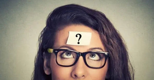 Person with glasses looking upwards, a question mark on a sticky note on their forehead.